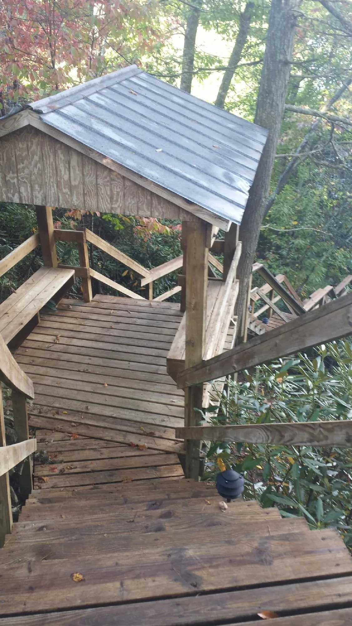 Metal roofed shelter over wooden steps on a wooded walkway — Skylight Repair & Installation work by our crew in Stowell