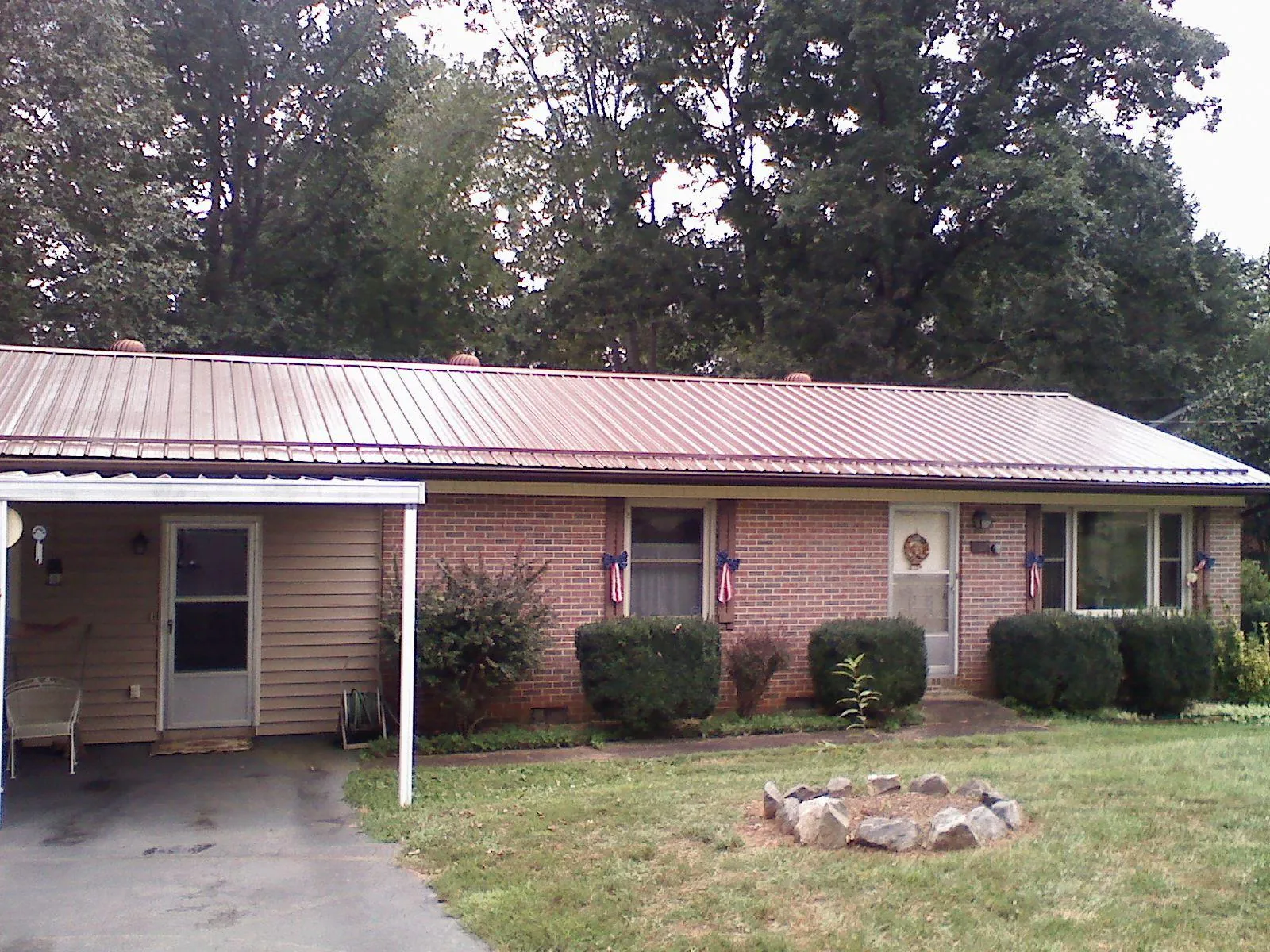 Bronze metal roof and carport on a brick ranch home — Roof Repair work by our crew in Stowell